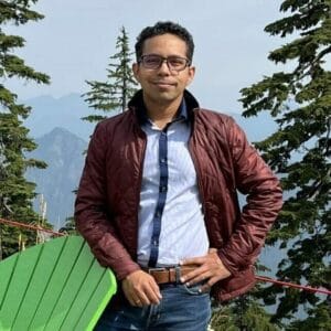 A man standing in front of a green chair with mountains in the background during the MC Fireside Chats event on July 26th, 2023.