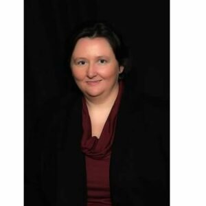 A woman, dressed in a black jacket and maroon shirt, is attentively participating in the MC Fireside Chats event on September 20th, 2023.