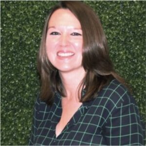 A woman smiling in front of a green wall during the MC Fireside Chats on September 20th, 2023.