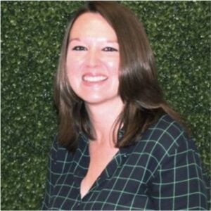 A woman smiling in front of a green wall during MC Fireside Chats.