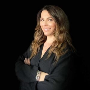 A woman is posing for a photo in front of a black background at the MC Fireside Chats on October 4th, 2023.