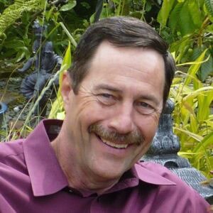 A man with a moustache smiling in front of a statue during the MC Fireside Chats on February 21st, 2024.