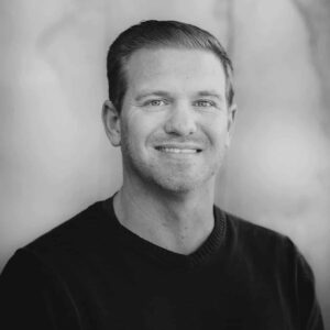 Portrait of a smiling man with short hair, wearing a black sweater, captured during the MC Fireside Chats on April 17th, 2024, against a blurred light background.