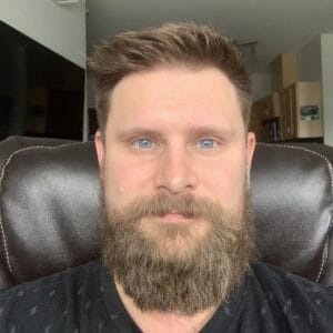 A man with a full beard and short hair is sitting in a brown leather chair indoors, looking directly at the camera. In the background, you notice kitchen cabinets and a ceiling light. The date May 22nd, 2024, could indicate when this snapshot was taken for MC Fireside Chats.